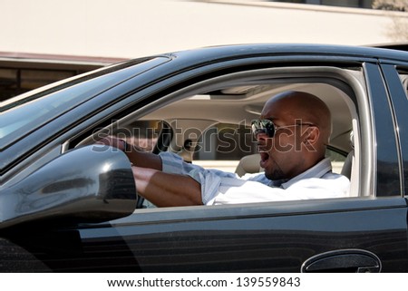 An irritated business man driving a car is expressing his road rage and anger.