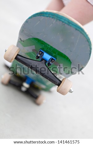 Close up of a skateboard popped up showing the front trucks and wheels. Shallow depth of field.