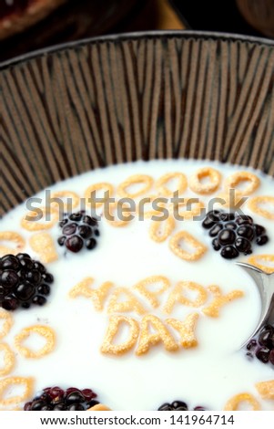 The words HAPPY DAY spelled out of letter shaped cereal pieces floating in a milk filled cereal bowl.