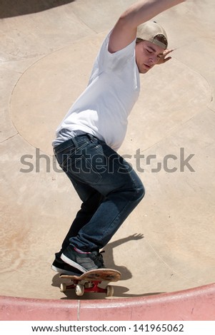 Action shot of a skateboarder skating in a concrete skateboarding bowl at the skate park.