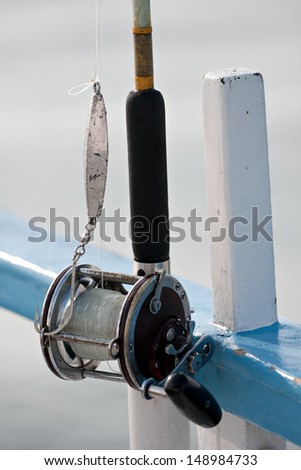 Close up detail of a bait casting deep sea fishing reel and rod set up with a jig and large hook. Shallow depth of field.