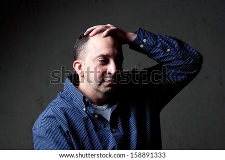 A middle aged man with a contemplative look on his face.  He could be worried or depressed about something.