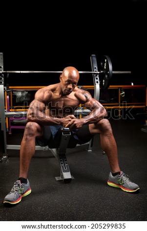 Weight lifter sitting at the bench press about to lift a barbell.