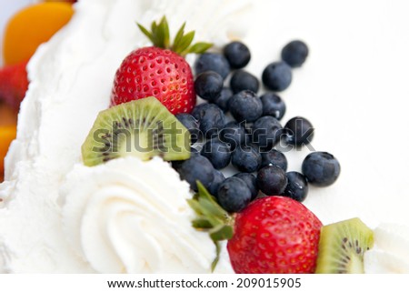 White frosted cake covered with fresh fruit toppings. Shallow depth of field.