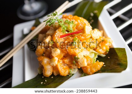 Thai crispy shrimp dish with apple and sesame seeds presented beautifully on a white square plate with chopsticks.