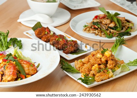 Varieties of Thai foods and appetizers covering a table. Shallow depth of field.
