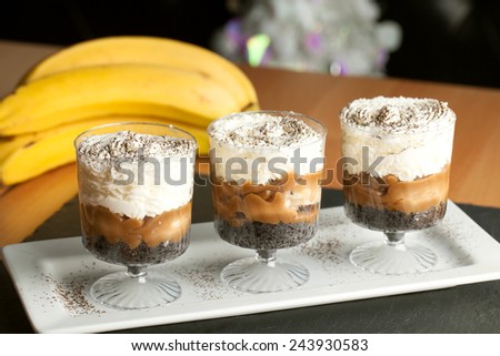 Banana caramel parfait desserts with fresh whipped cream and chocolate cookie crumbles.