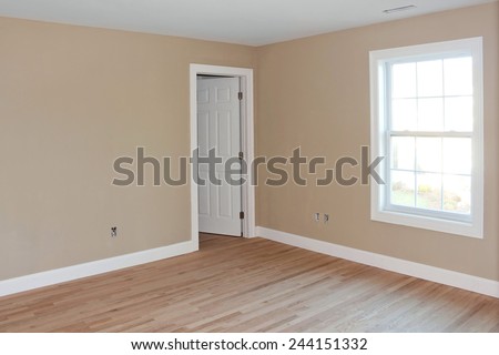 Newly constructed house interior room with unfinished wood floors window and closet door.  Electrical connections are partially unfinished.