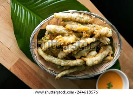 Thai style appetizer of fried tempura asparagus with dipping sauce. Shallow depth of field.