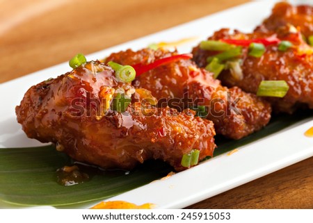 Thai style spicy chicken wings appetizer on a contemporary white plate