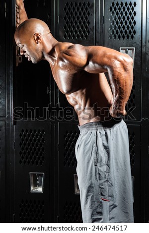 Portrait of a muscle fitness man reaching for his lower back in pain