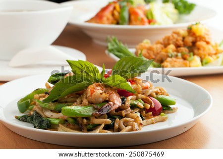 Varieties of Thai foods and appetizers covering a table. Shallow depth of field.