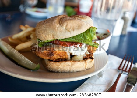 Fried fish sandwich with tartar sauce and french fries.