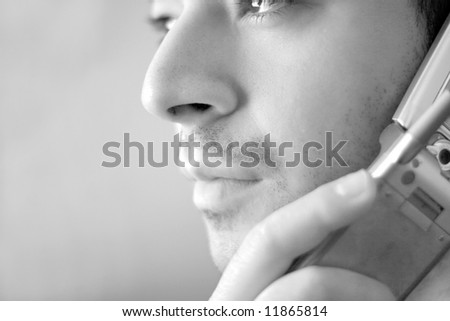 Black and white portrait of a young man on his cell phone.  He is listening with a  serious look of concern on his face.