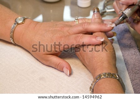 A professional nail technician working on a clients nails with the sander.