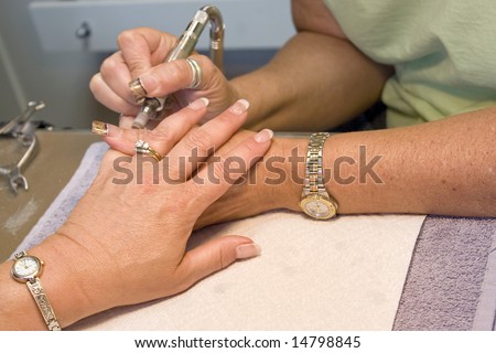 A professional nail technician working on a clients nails.