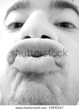 An extreme closeup of a young man trying to kiss in black and white.  Shallow depth of field.