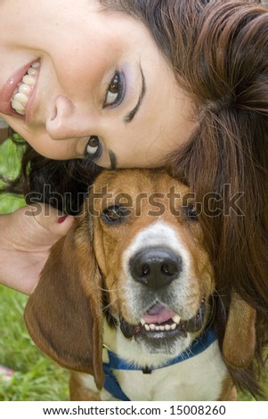 A pretty girl posing with her beagle dog - they both seem to be smiling.