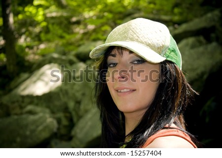 A girl dressed in summer clothes posing out in the woods.