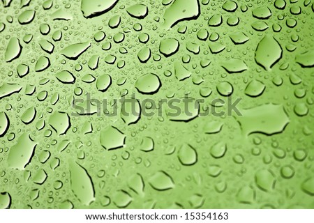 A macro of some beautiful water droplets over a lime green background.  Shallow depth of field.