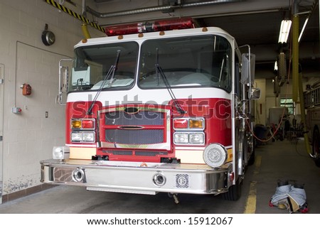 A fire truck is parked in the bay with all of the fire fighting equipment and gear ready to go.
