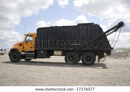 A modern garbage truck over a bright blue sky.