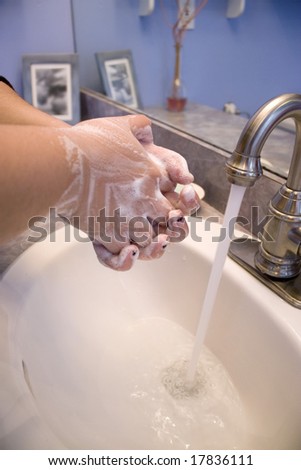 A person washing their hands in the bathroom.