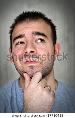 A young man with his hand on his chin thinking an important decision.