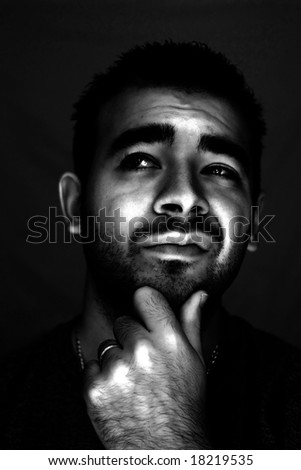 A man with his hand on his chin thinking an important decision - high contrast black and white.