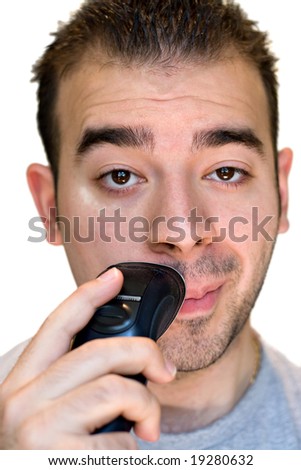 A closeup of a young man shaving his face with an electric shaver.