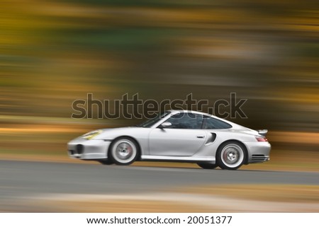 A modern sports car speeding along the road with a motion blur effect.