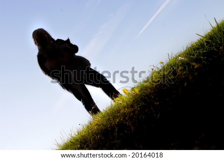 A young female student posing on a grassy hill on the school campus