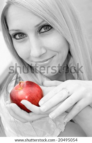 A young blond posing with an apple - black and white with selective color.