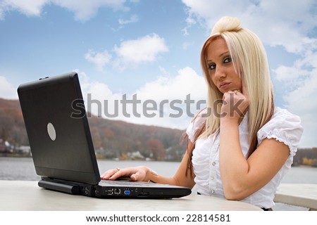 A beautiful young blonde woman in a mobile business setting with her laptop.