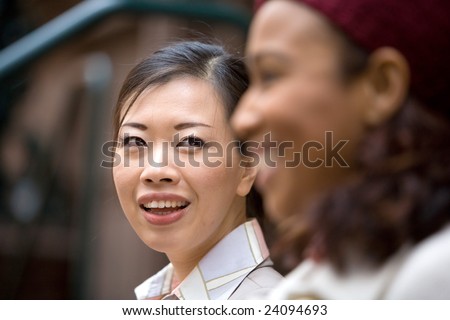 Two business women having a casual meeting or discussion in the city. Shallow depth of field.