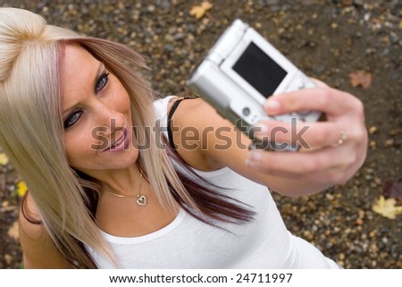 A young woman taking pictures of themselves with a digital camera.
