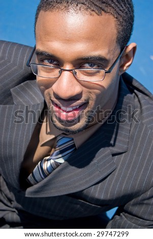 African American man in a business suit with eye glasses smiling happily.