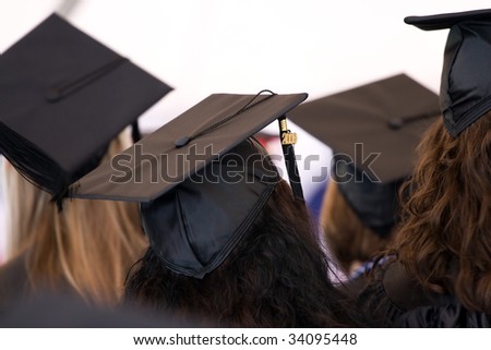 A group of college or high school graduates wearing the traditional cap and gown.  Shallow depth of field.