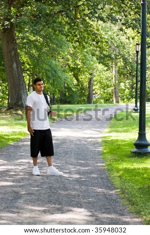 A young man walking on campus with his backpack and a positive attitude.