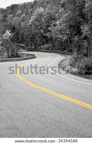 A curved New England road with selective isolated color and the center double lines in yellow.
