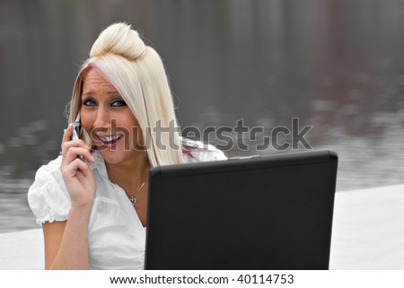 A beautiful young woman in a mobile business setting with her cell phone and laptop.
