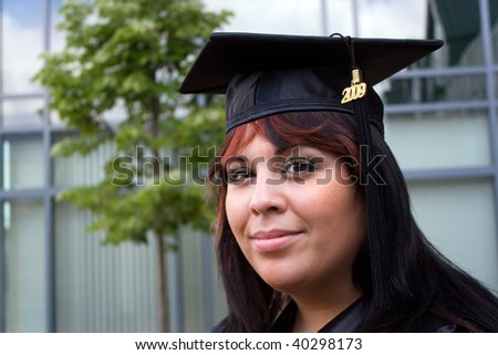 A recent graduate posing in her cap and gown.