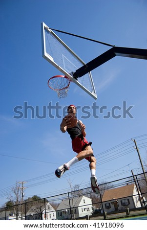 A young athlete driving to the basketball hoop for a lay up or slam dunk.