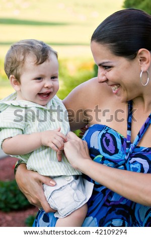 A young mother tickles her baby happily.