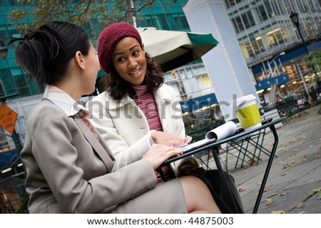 Two business women having a casual meeting or discussion in the city. Shallow depth of field.