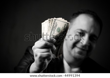 A happy man holds a handful of cash with selective color.