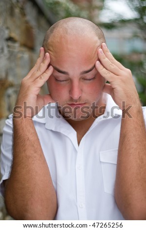 A stressed out young man grabs his head in annoyance from stress or a headache.