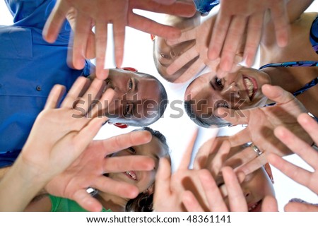 A happy family posing in a group huddle formation and waving at the camera.  Intentional motion blur of the hands.