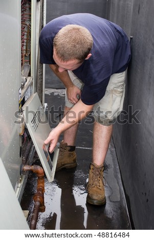 An HVAC repair technician repairing or working on a commercial heating air conditioning unit.
