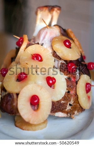 A large 12 pound ham all garnished with cloves pineapples and cherries baked steaming hot out of the oven.  Shallow depth of field.